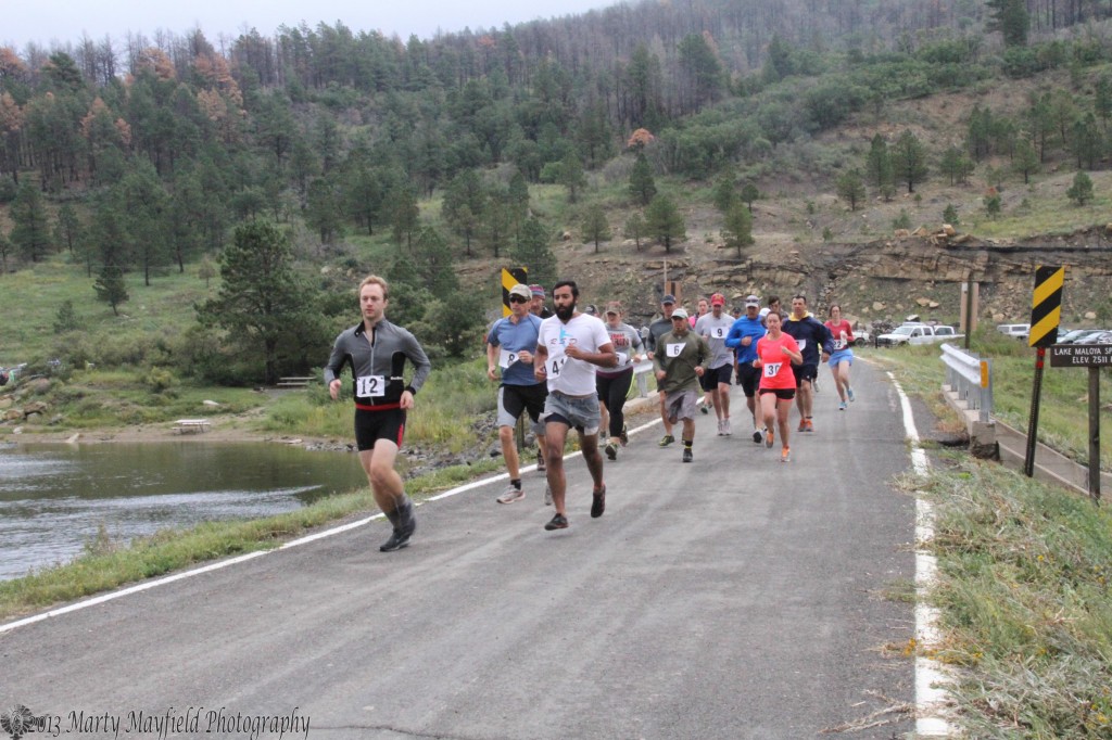 Lead by Cole Shindler, runners make their way over the Lake Maloya dam to start off the Master of the Mountain Adventure Relay Saturday morning.