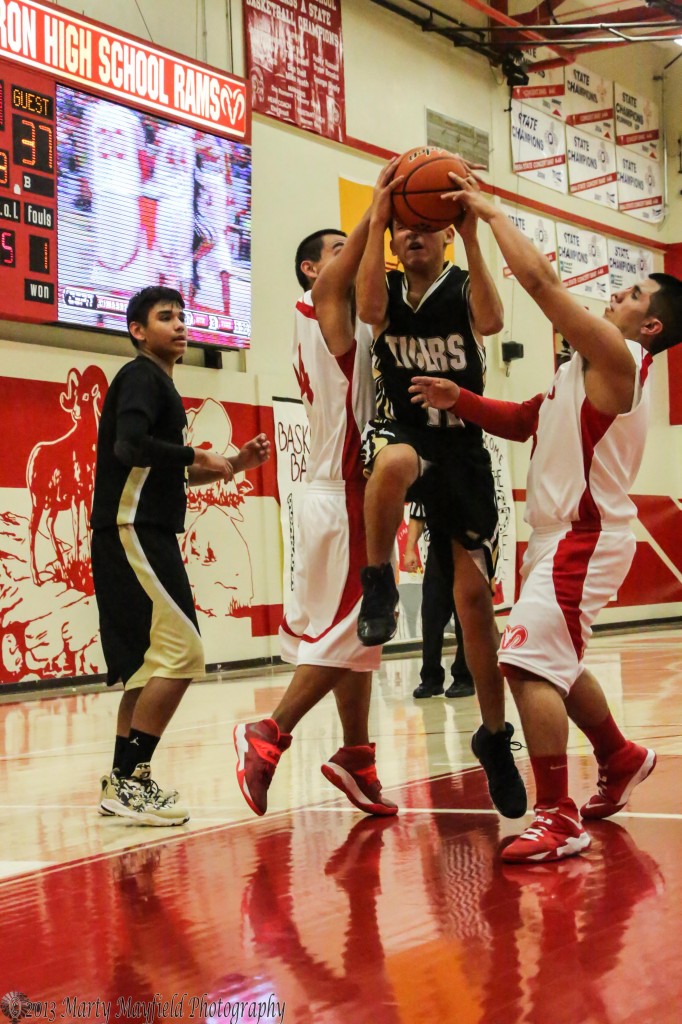 Jodus Gonzales threads the needle on his way up for a lay-up during the game in Cimarron Saturday night.
