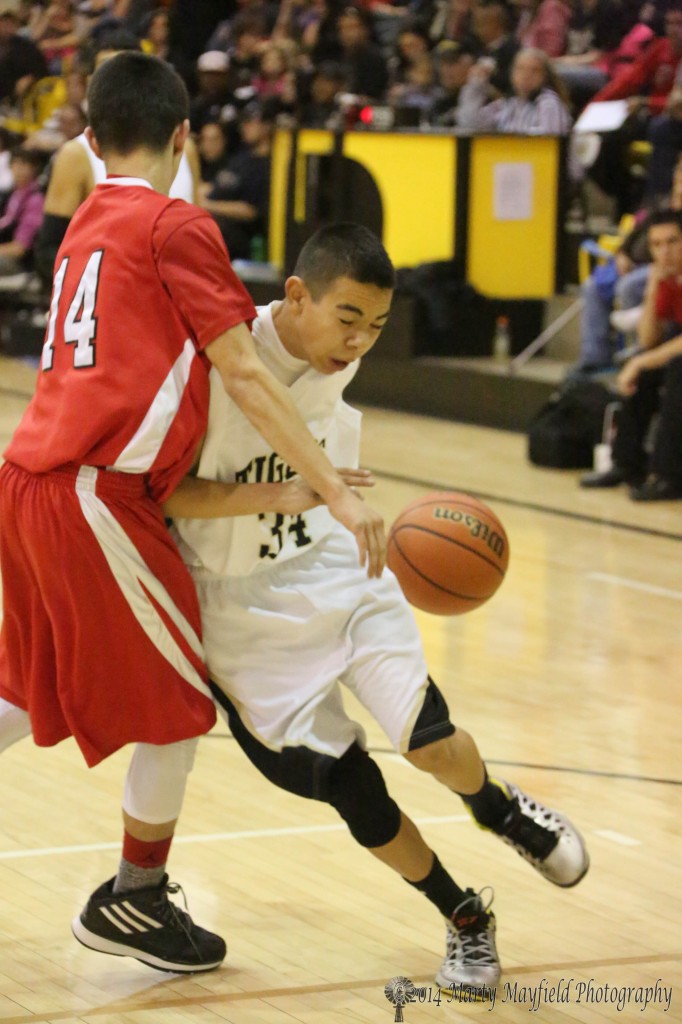 Jesse Espinoza tries to squeeze around Cardinal Ishmael Martinez on his way to the basket during the JV game Friday evening in Tiger Gym 