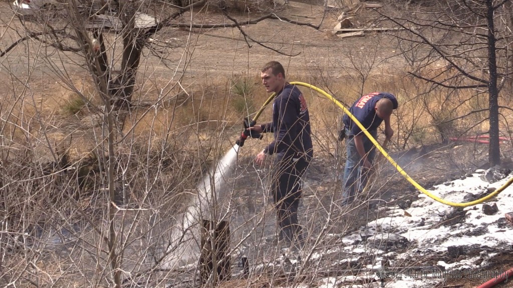 Firemen Jacob Butt and Anthony Burke work on hot spots after extinguishing a small grass fire on Maxwell Street Monday afternoon. 