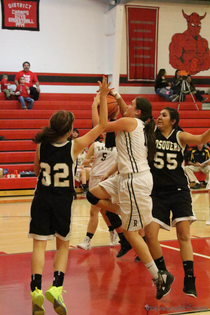 Tarryn Trujillo drives the lane as Gabby Vigil (55) and Taylor Libby (32) work in for the block.