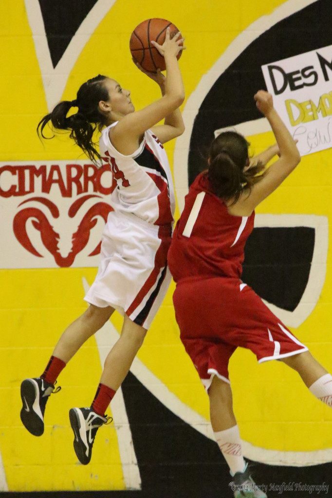 Anjelica Montoya goes for the jump shot as Angel Gonzales(1) tries for the block. Anjelica put in 14 points during the championship game with Cimarron in the 78th Annual Cowbell Tourney.