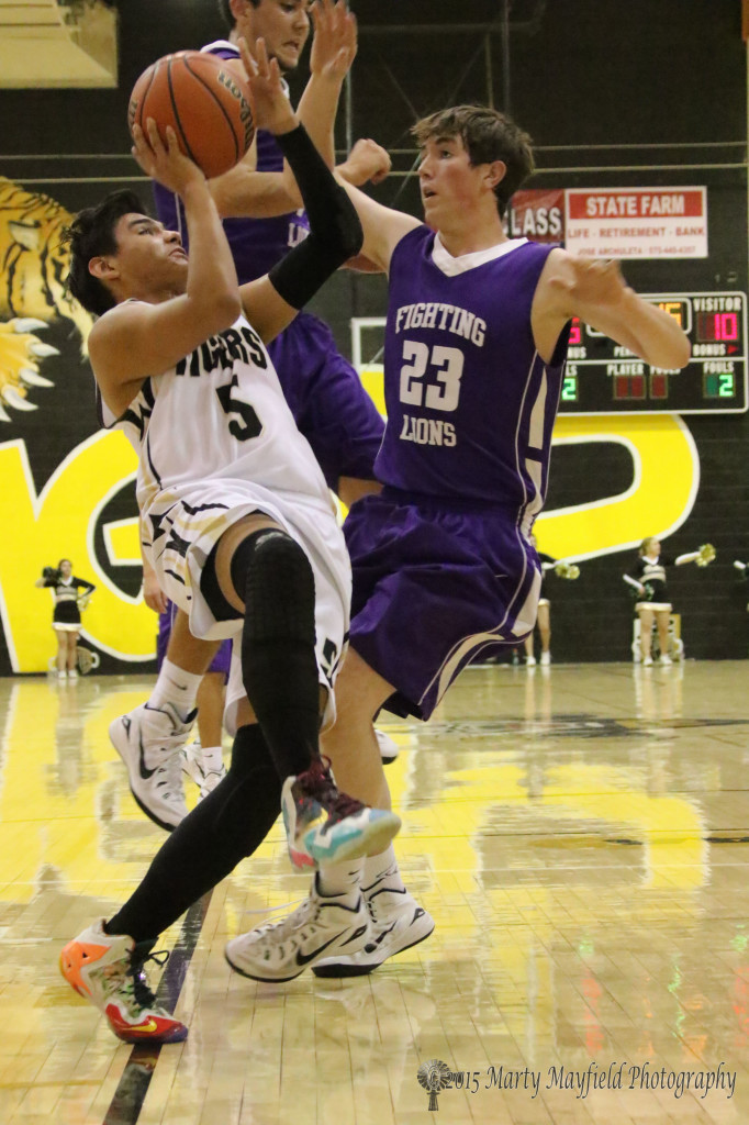 A little off balance Austin Jones take the shot as Pryce Marez (23) goes for the block and draws the foul.