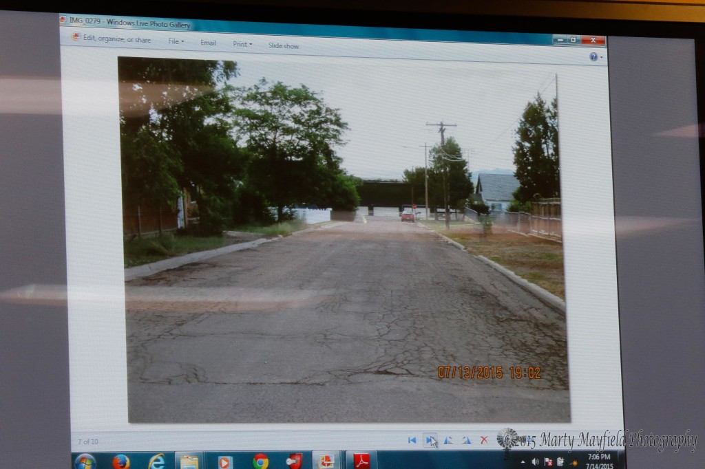 The cracked pavement on the street leading down tot he football field.