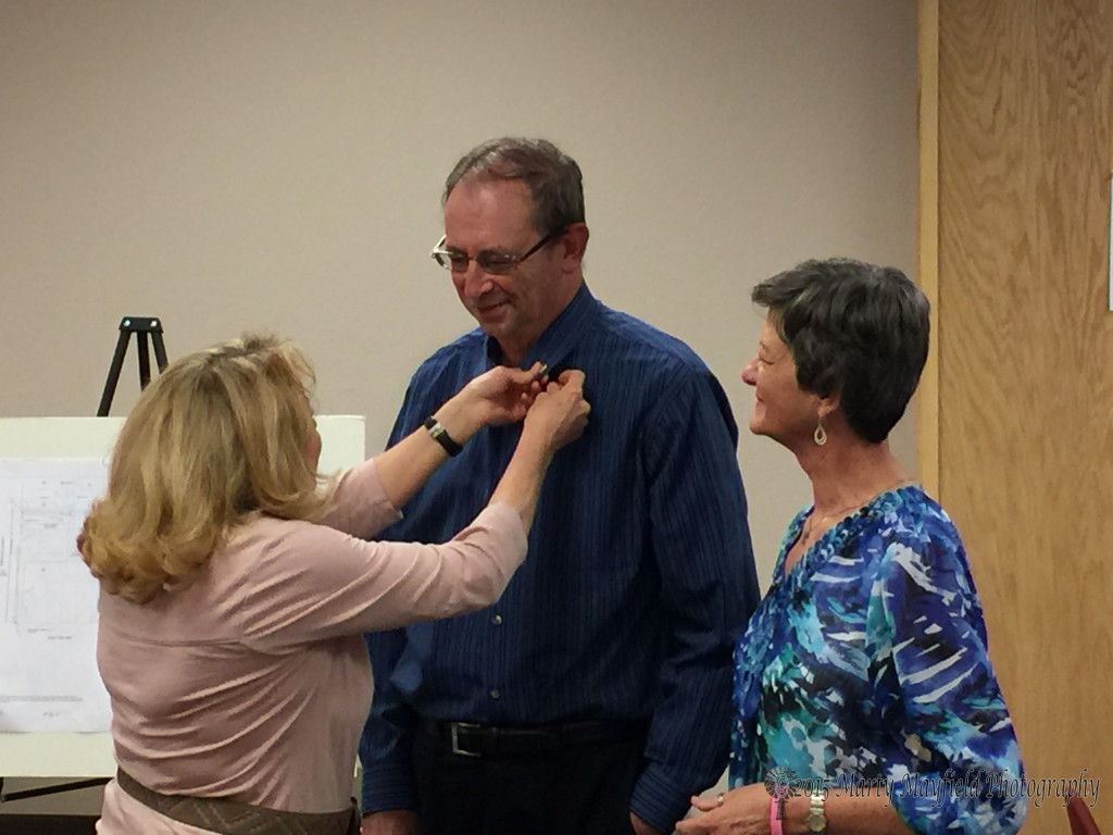 Commissioner Linde Schuster pins a pin on Frankie Mahannah for his You Rock Award. Methodist Preacher Adrianne Coleman was on the committee that selected Mahannah.