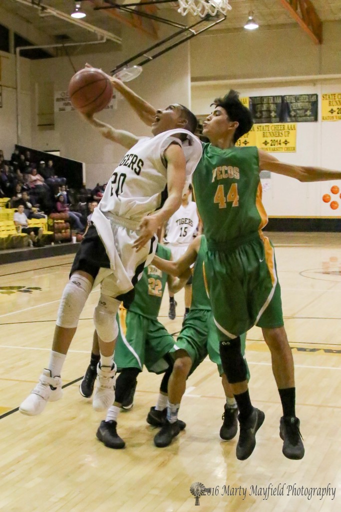 Christian Abeyta (44) gets a hand on the ball as Richie Acevedo (20) goes up for the lay-up during the JV game with Pecos Friday evening in Tiger Gym