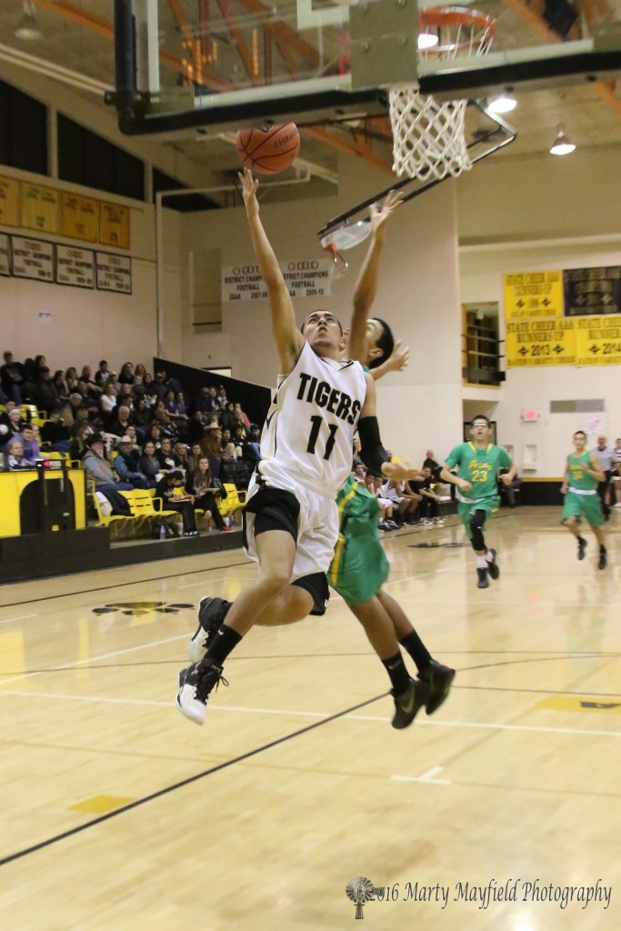 Dustin Segura (11) squeezes by a Pecos' Carlos Cordova on his way in for the lay-up Friday evening