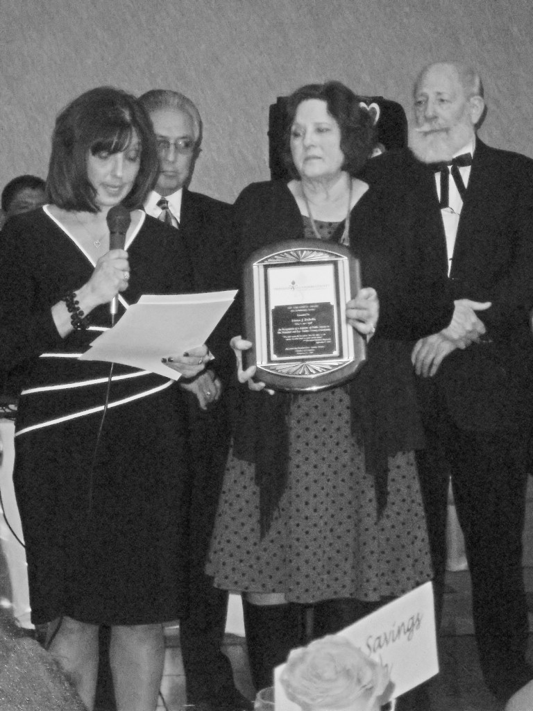 Kathleen Griego, Ed Griego and John Schecter (at right) present the 2105 Chenowith Award to Laura DeBella.  Photo by Joy Gipson.