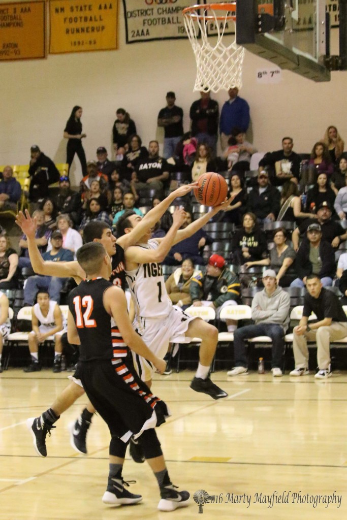 Jose Zamora reaches in for the ball as Jesse Espinoza goes for the basket during the second half of play in Tiger Gym