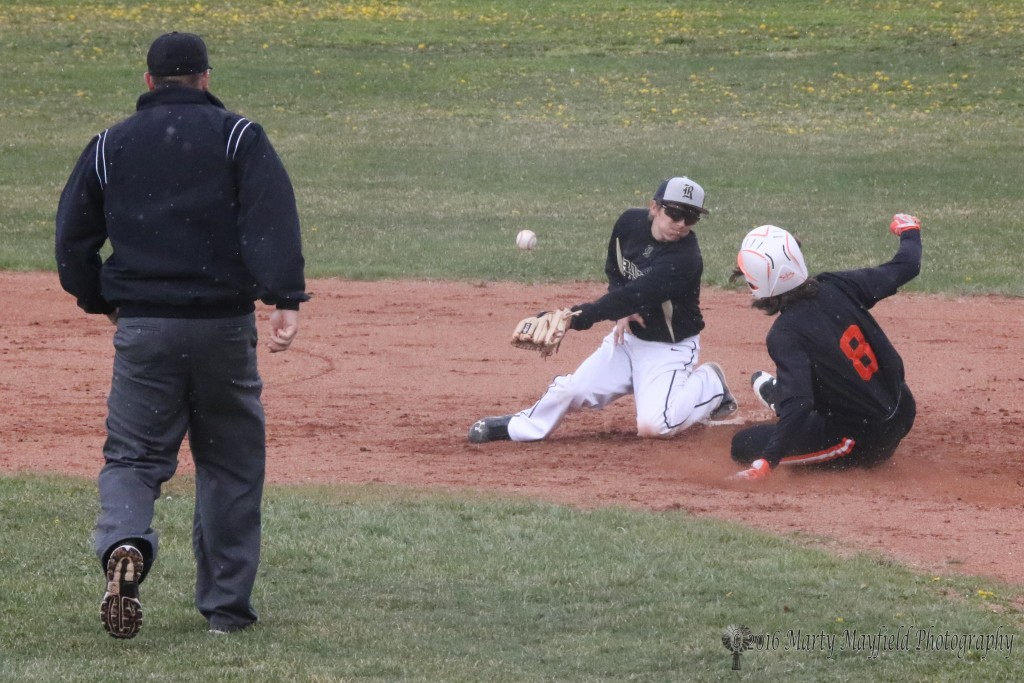 Damien Martinez has trouble fielding the ball as it bounces off the ground and ?? slides safe into second