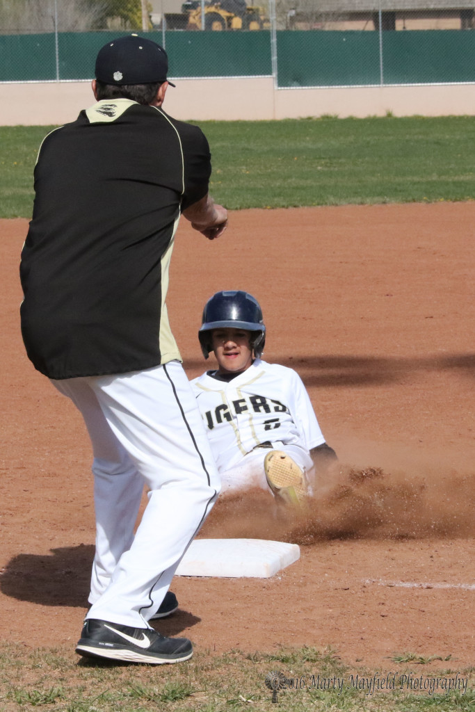 Coach Mike Marez signals Mateous Samora to slide and hold up at third. 