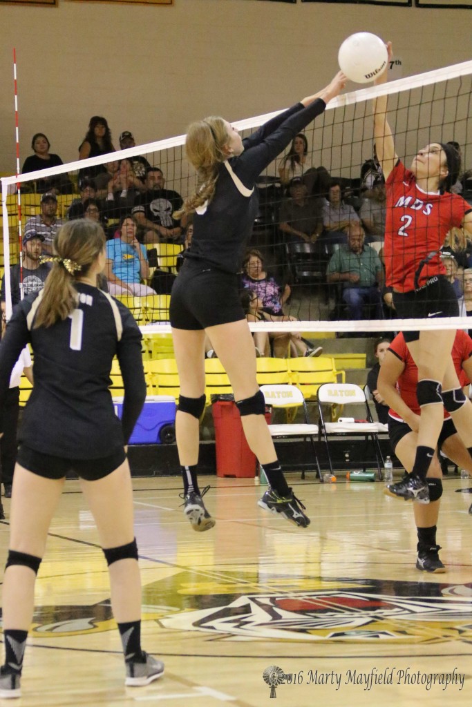 Ariana Rodriguez hits the ball as Alina Pillmore goes up for the block and just gets a finger on the ball. 