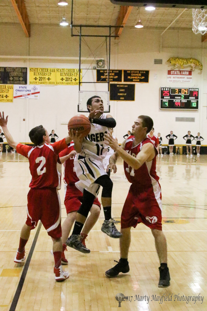 Dustin Segura (11) drives through traffic as Morgan Sahd (2) and Austin Luksich try to prevent the shot Thursday in Tiger Gym.