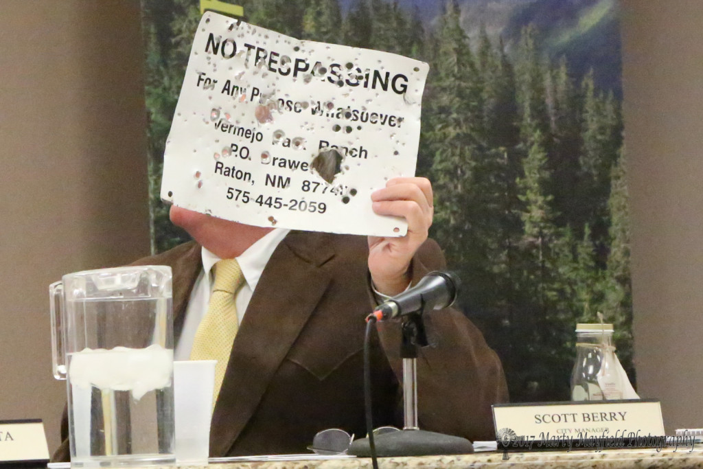 City Manager Scott Berry holds up a sign that the Vermejo Ranch brought in to him as a result of indiscriminate shooting on the Old Pass Road