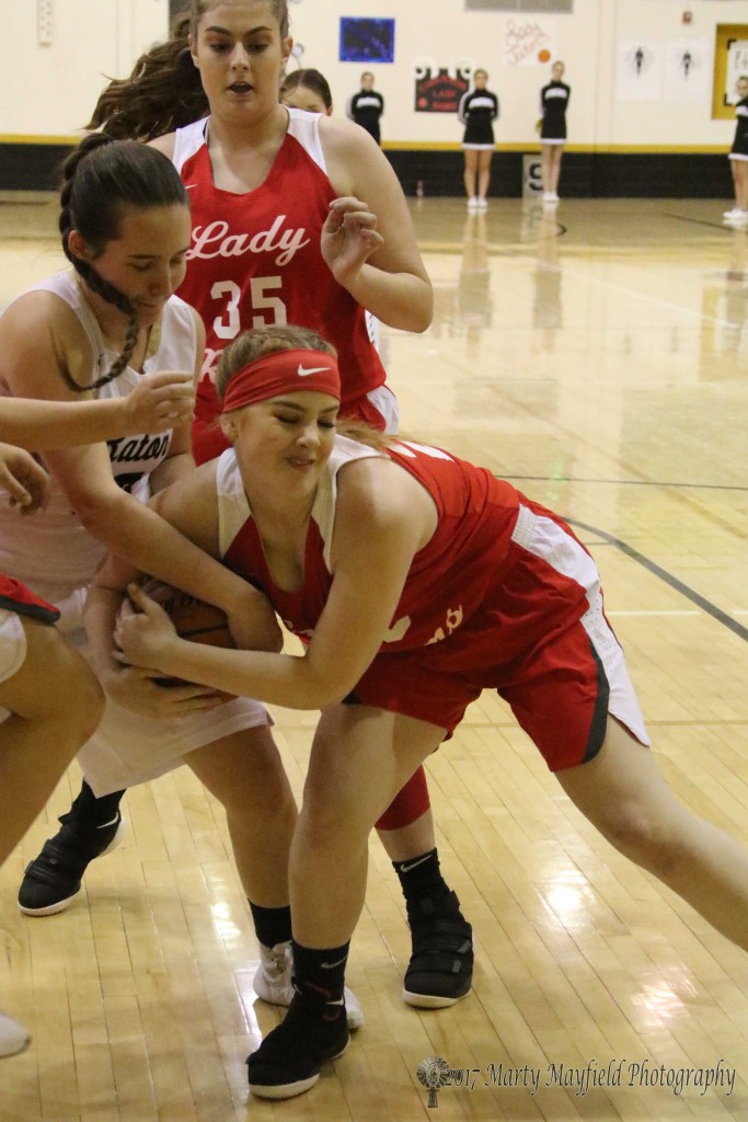 Halle Medina and Samantha Ogata wrangle for the ball as Olivia Perryman looks on Friday night in Tiger Gym during the 81st Annual Cowbell Tourney.