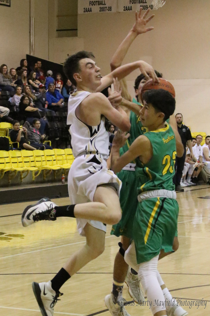 Raton's John Ware meets up with Devin Gonzales and Juan Varela as he tries to go for the basket during the district game in Raton Saturday evening.