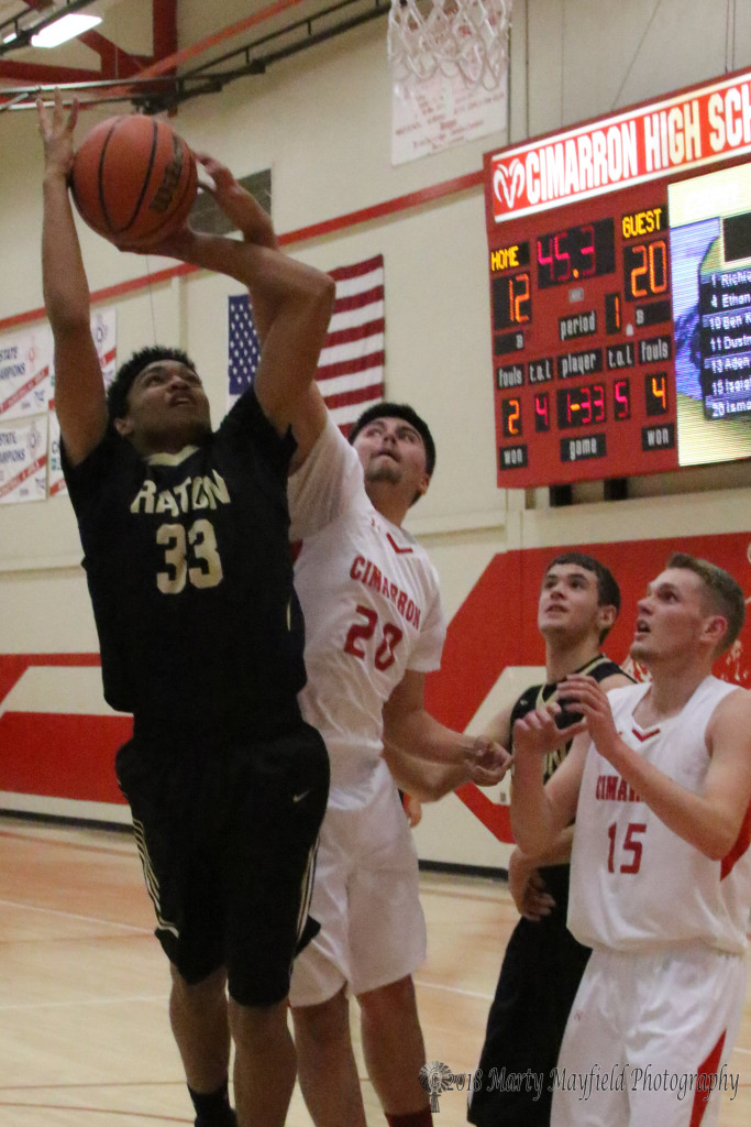 Darien Lewis goes up for the shot as Austin Vargas gets a hand on the ball to disrupt the shot Thursday evening in Cimarron. 