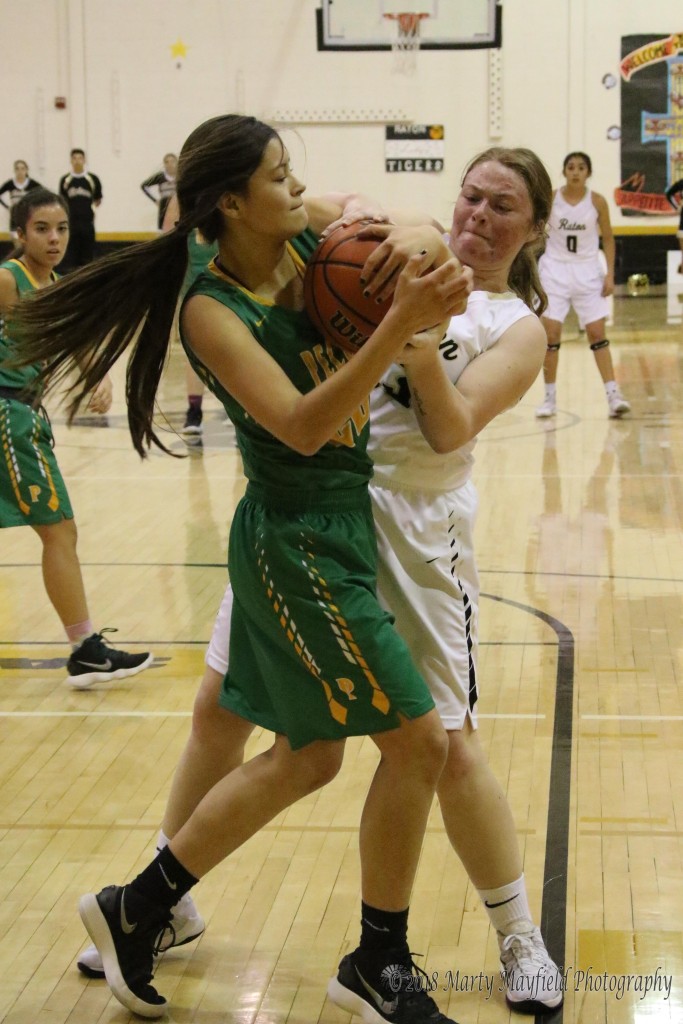 Jadyn Walton and Faith Flores struggle for the ball during the district game in Tiger Gym Saturday evening. 