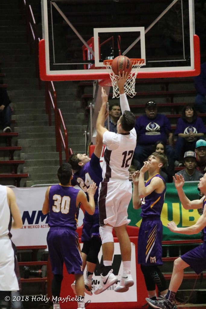 6' 6" Jordan Jasso goes up with the short jumper well above the head of Jeremy Archuleta early in the state title game in the The Pit in Albuquerque.