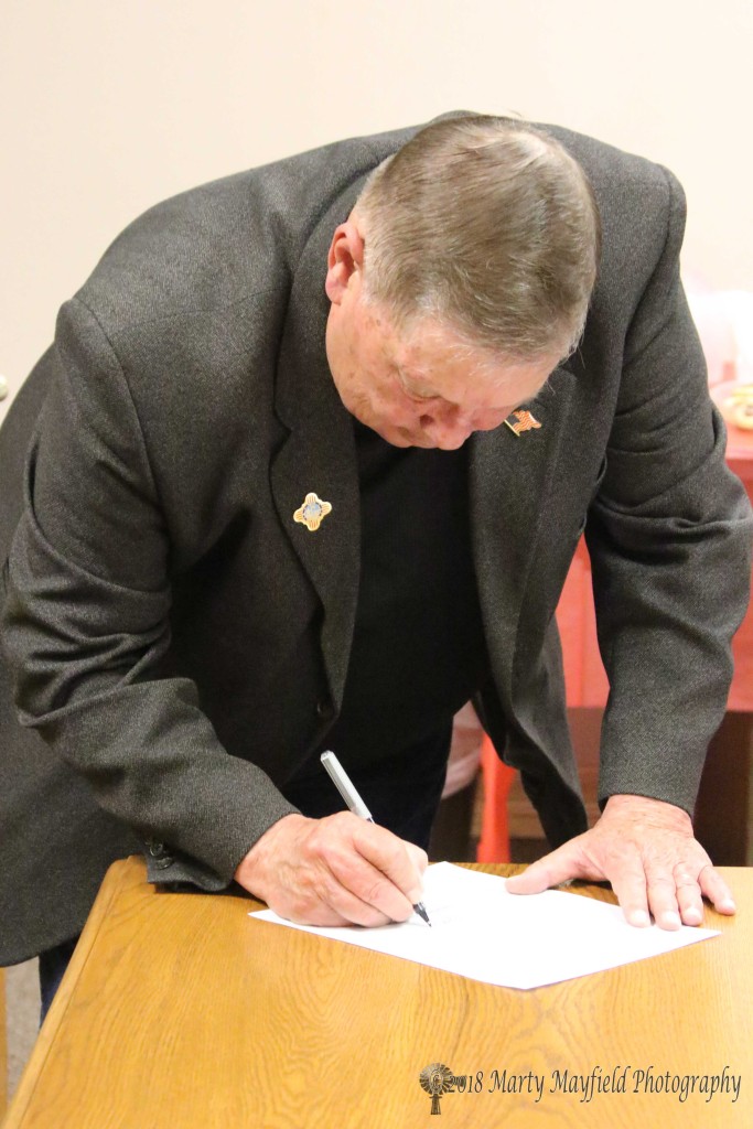 Ron Chavez signs his form accepting the Oath of Office for a return trip as Raton City Commissioner.